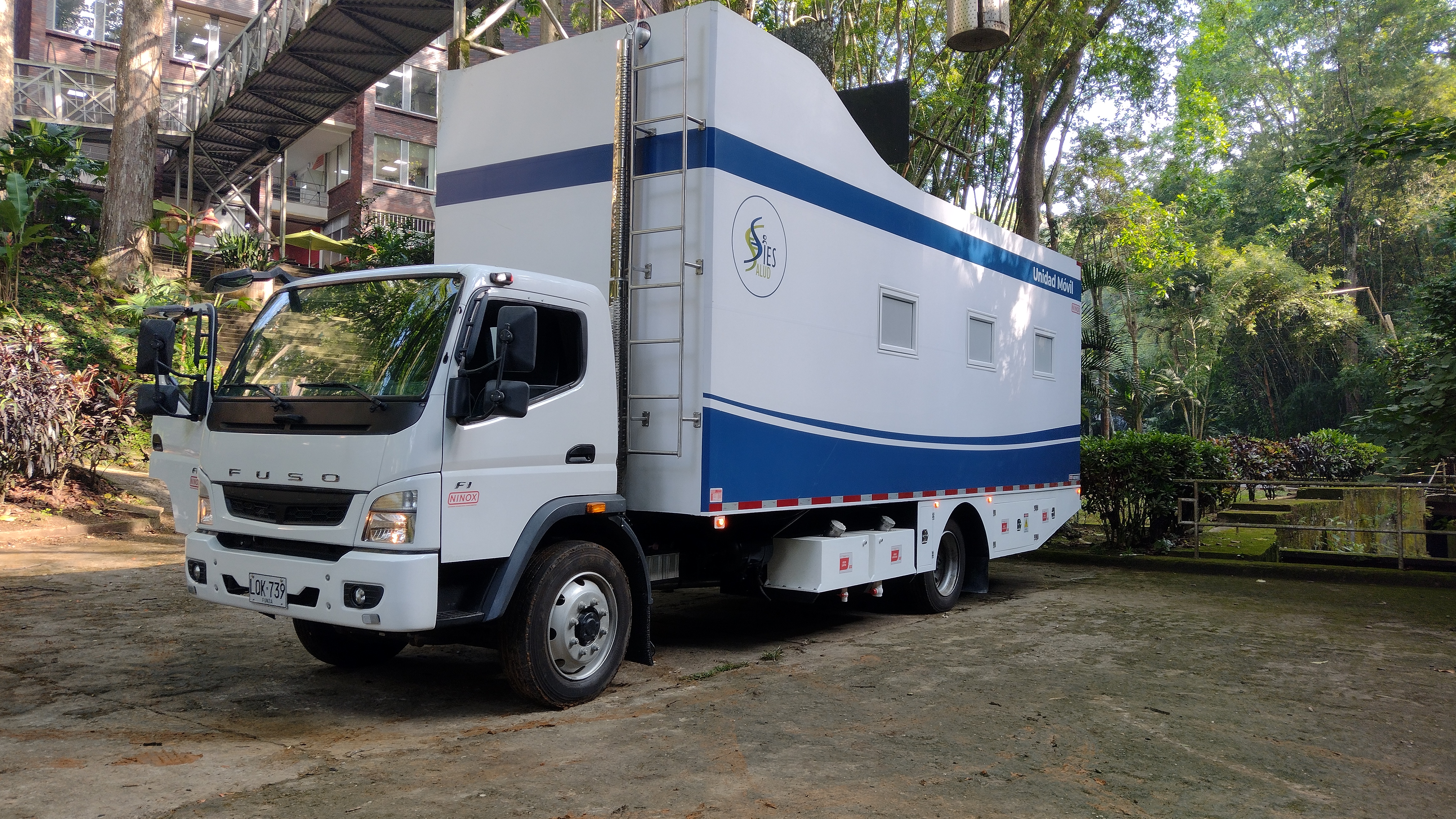 The completed unit ready for service: NINOX coachwork on a Mitsubishi Fuso F1 chassis, carrying the SIES Salud identity in a tropical Colombian setting.